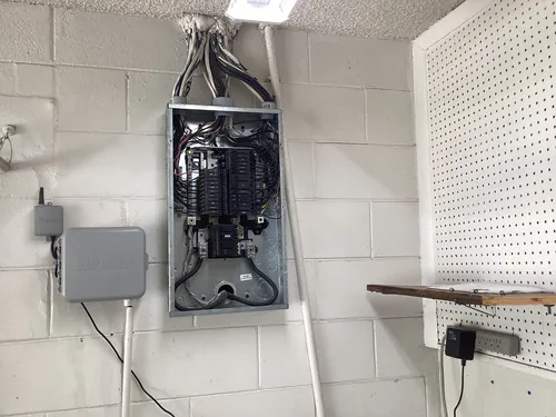 Open load center on the garage block wall of a Longwood home with new home run cables formed into the top of the enclosure