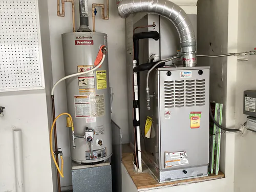 A.O. Smith ProMax gas water heater and Bryant furnace with a flexible metal conduit whip in a Longwood garage alcove