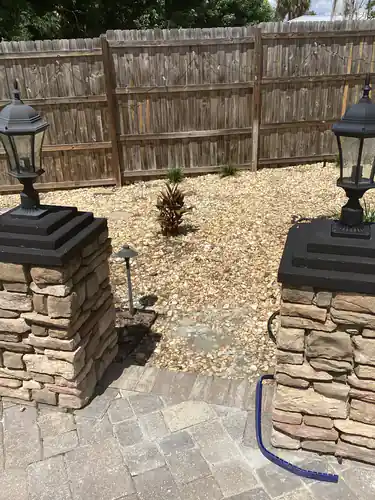 Post top lanterns on stacked stone columns and a low voltage path light beside the paver patio at the Longwood home