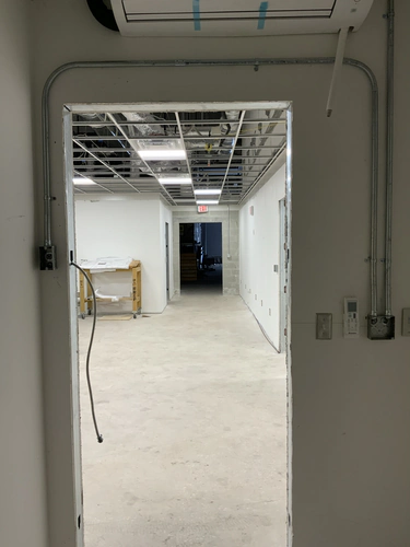 Office corridor at the EMS warehouse with suspended ceiling grid, exit sign and conduit stub ups