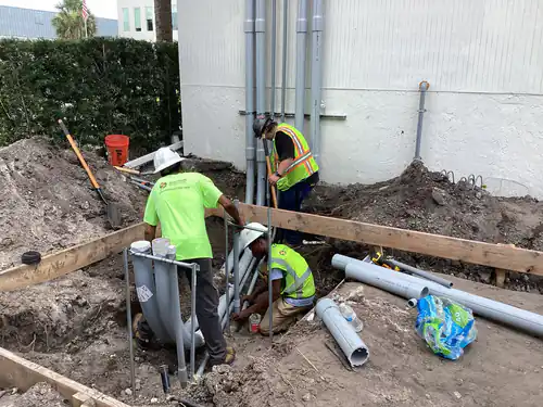 Three Spectrum Electric electricians assembling an underground PVC conduit bank beside the EMS warehouse
