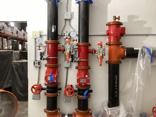 Sprinkler risers with tamper and flow switches wired in flexible conduit at the EMS warehouse