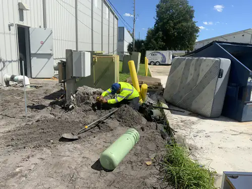 Electrician working in an open trench beside the utility cabinets outside the EMS warehouse