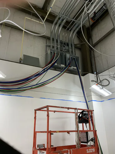 Large feeder conductors dropping from a wall mounted pull box to a scissor lift inside the EMS warehouse