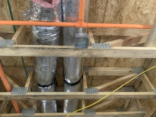 Orange conduit and a ceiling box run above the floor trusses at Hawthorne Heights