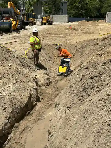 Two workers compacting a trench with a plate compactor on the Hawthorne Heights site