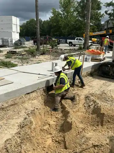 Two workers cutting into the ground beside a finished concrete walk at Hawthorne Heights