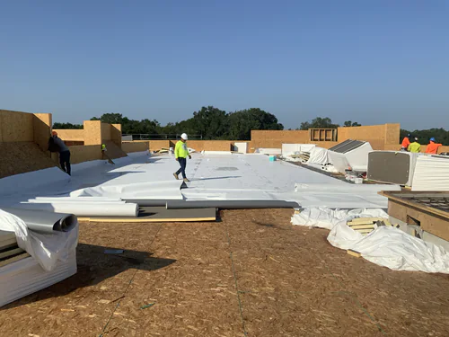 Roof deck at Hawthorne Heights with membrane being rolled out over the sheathing