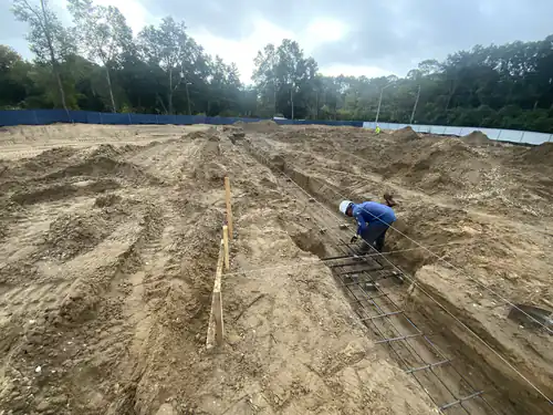 Worker tying rebar in the footing trenches at the Hawthorne Heights site