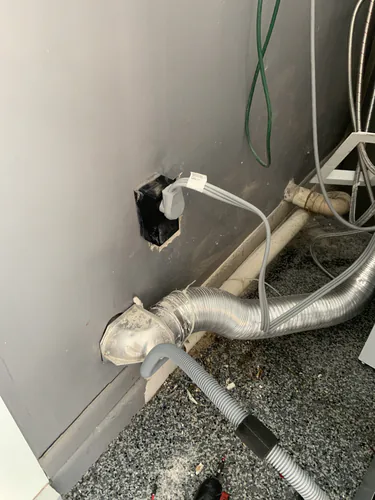 New 240 volt dryer receptacle in a black surface housing with the dryer cord plugged in above the vent duct in Maitland