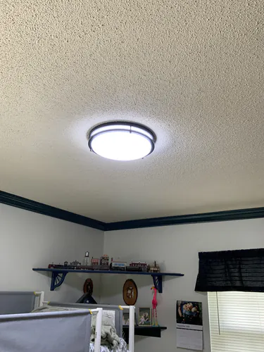 New LED flush mount ceiling light switched on in a Casselberry bedroom with a textured ceiling and dark crown molding