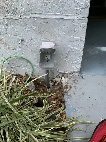 New outdoor outlet with a gray in use cover mounted on the stucco wall of a Casselberry home on a PVC conduit riser