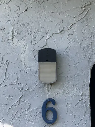 New slim LED porch light mounted on textured stucco above the house number of a Casselberry home
