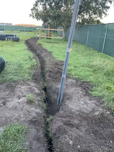 Conduit trench cut across the grass toward the Massey Cadillac building