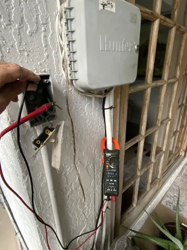 Klein clamp meter reading 0002 on the conductors of the outdoor master switch next to a Hunter irrigation controller in Oviedo