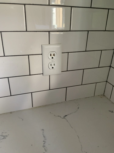 Scorched upper receptacle on a white subway tile kitchen backsplash in Oviedo, with brown discoloration around the slots