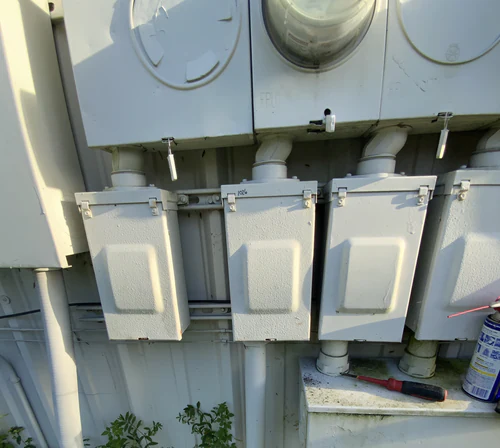 Row of outdoor meter sockets on an Orlando service wall with a gray main disconnect enclosure under each meter