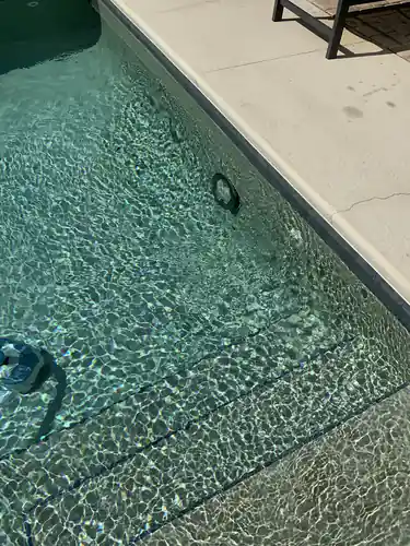 Underwater pool light seated back in its wall niche below the tile line of a Winter Park pool with clear water over the steps
