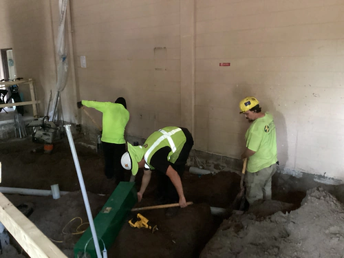 Spectrum Electric crew hand digging a conduit trench inside the Hunter's Creek pump building