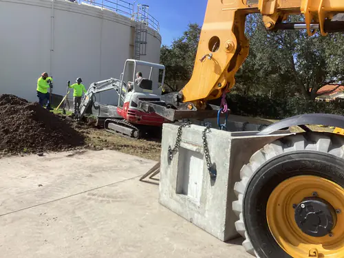 Telehandler setting a precast pull box beside the ground storage tanks at the Hunter's Creek water facility