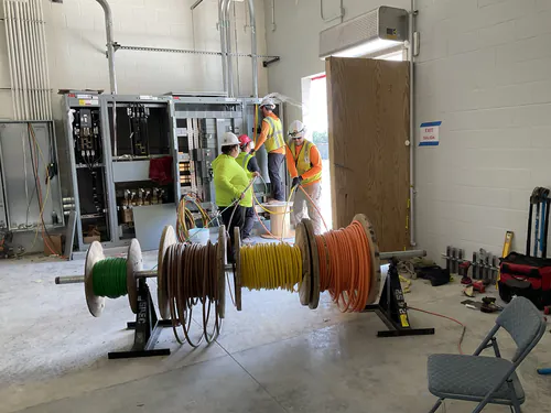 Spectrum Electric crew pulling feeders from wire reels into ABB switchboard sections at Lady Lake Market