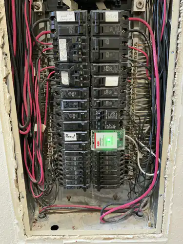 Rewired Winter Park panel with red and black conductors dressed along both gutters and an ABB surge protective device lit green